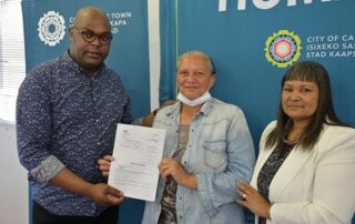 Councillor Booi with beneficiary Ms. Desiree Mchelm and Councillor Michelle Adonis . Image credit: COCT
